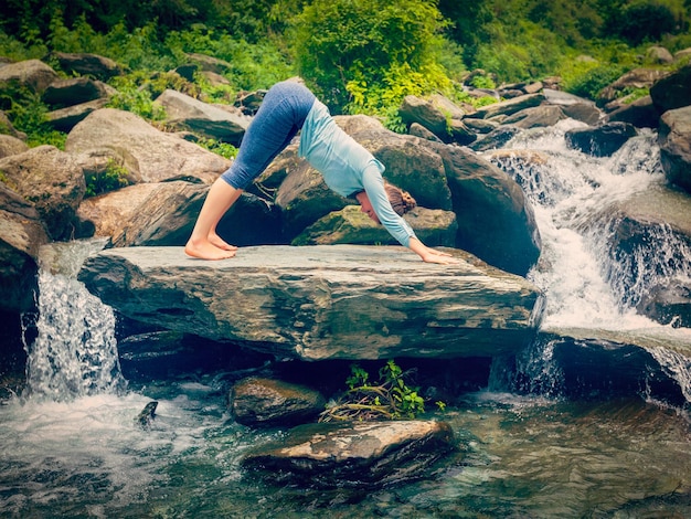 Young sporty fit woman doing yoga oudoors at tropical waterfall