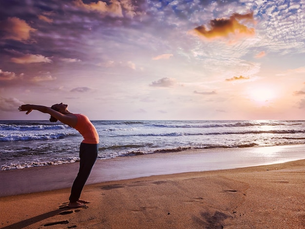 Young sporty fit woman doing yoga Sun salutation Surya Namaskar