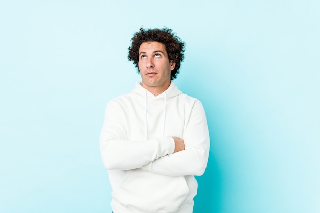 Young sporty man against a blue wall tired of a repetitive task.