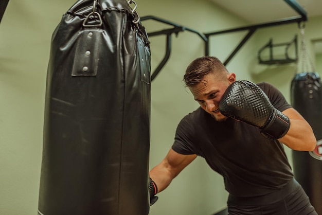 Photo a young sporty man exercise intensively while punching boxing bag in a gym