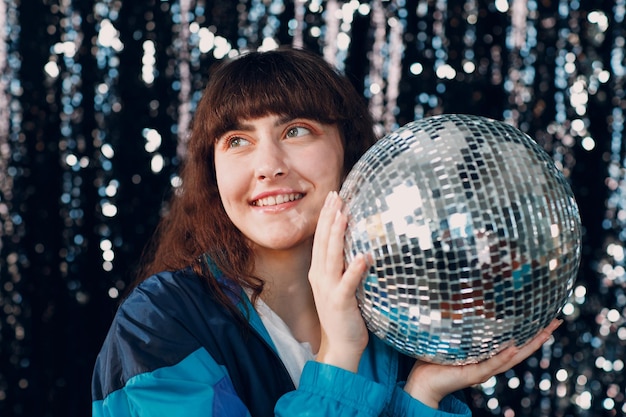 Young sporty woman 80 and 9039s style 90s fashion positive girl at disco party with disco ball in hands