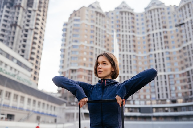 Young sporty woman doing exercises with rubber band outdoor