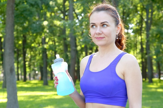 Young sporty woman drinking water from a bottle