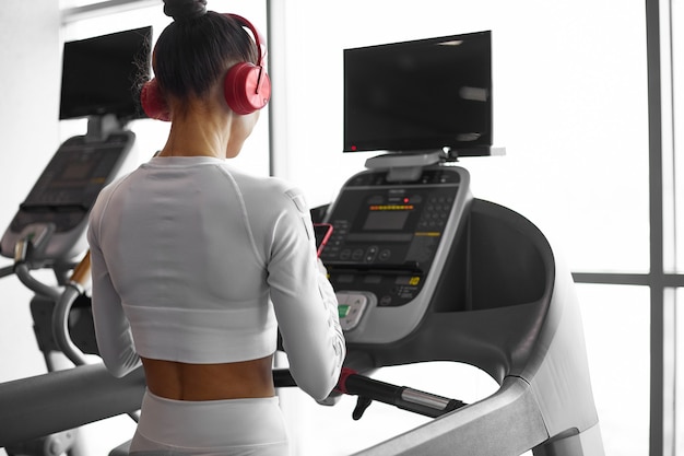 Young sporty woman running on treadmill. Gym workout