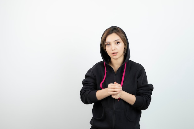 Young sporty woman standing and showing fists against white wall . High quality photo