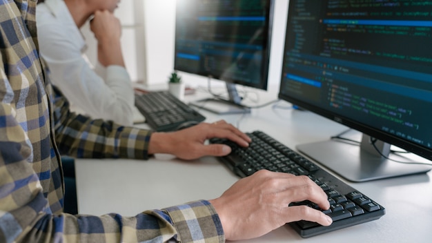 Young startup Programmers Sitting At Desks Working On Computers screen for Developing programming and coding to find solution to problem on New Application.