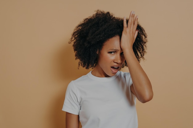 Young stressful african woman with hand on forehead suffering from strong headache or head migraine