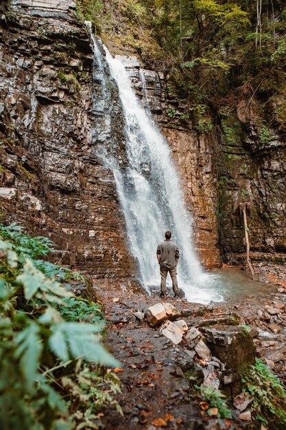 Young strong man hiker looking the waterfall