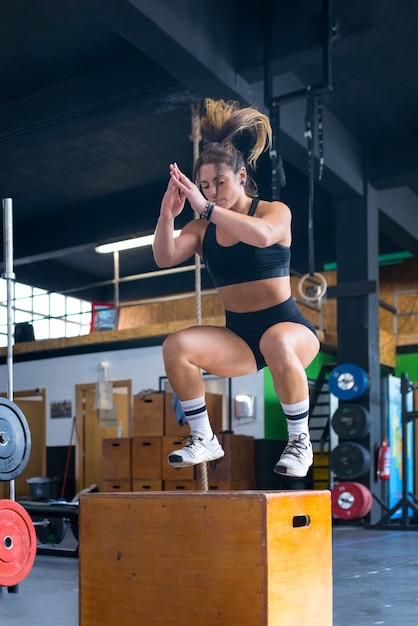 Young strong sweaty fit muscular girl with big muscles doing box jump hardcore crossfit