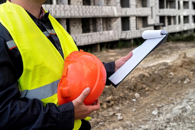 Young strong workers in special uniforms compare construction work with the plan on paper Construction concept