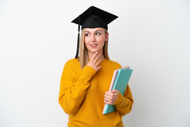 Young student caucasian woman isolated on white background looking up while smiling