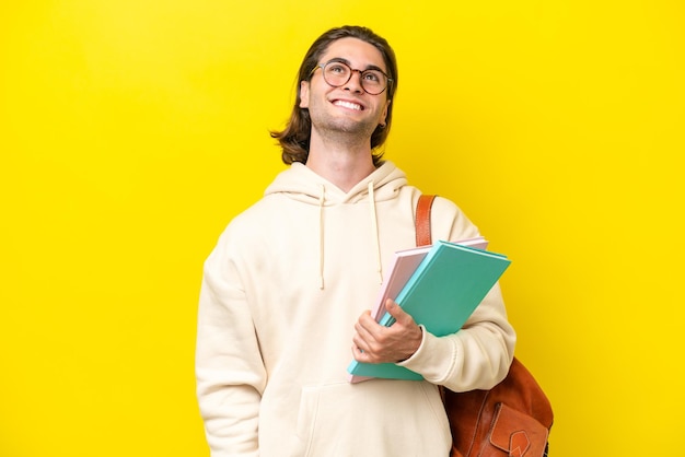 Young student handsome man isolated on yellow background thinking an idea while looking up