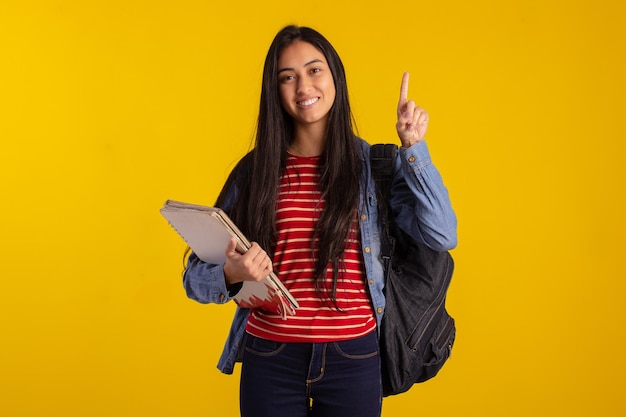 Young student holding backpack and books in studio photo