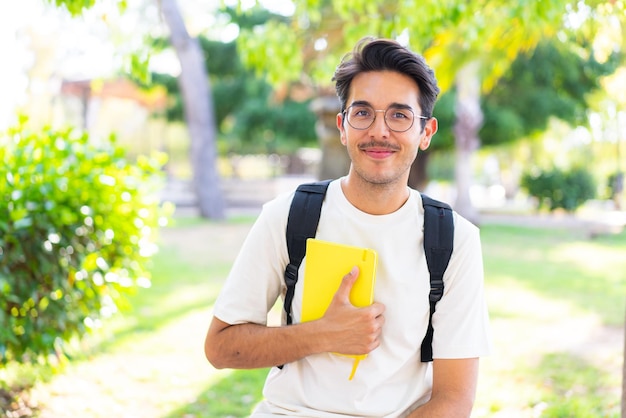 Young student man at outdoors holding a notebook