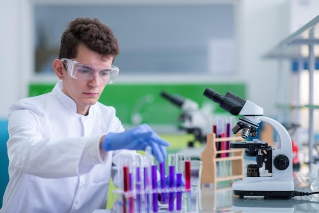 young student with protective glasses making chemistry experiment in bright laboratory,education and medicine concept