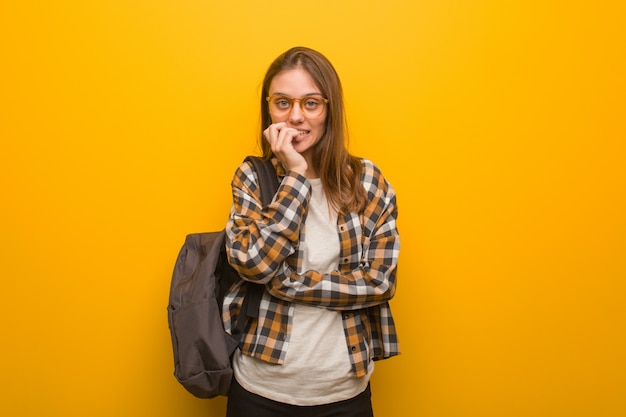 Young student woman biting nails, nervous and very anxious