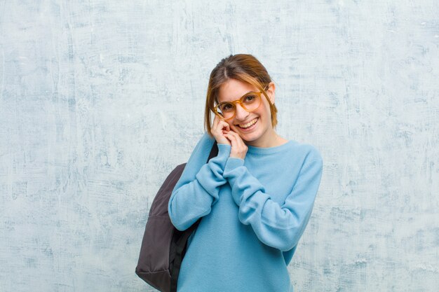 Young student woman feeling in love and looking cute adorable and happy smiling romantically with hands next to face