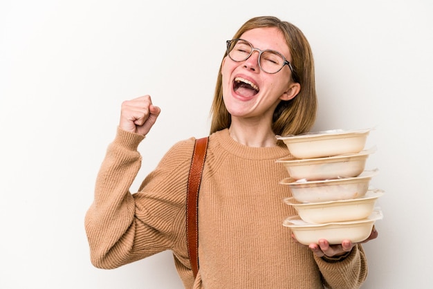 Photo young student woman holding a toppers isolated on white background raising fist after a victory, winner concept.