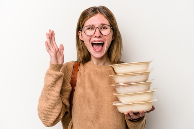 Young student woman holding a toppers isolated on white background receiving a pleasant surprise, excited and raising hands.