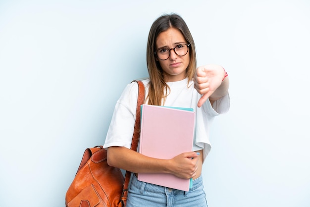 Young student woman isolated on blue background showing thumb down with negative expression