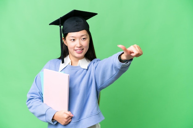 Young student woman over isolated chroma key background giving a thumbs up gesture