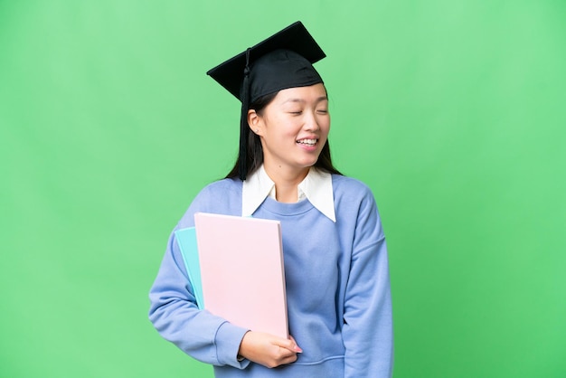 Young student woman over isolated chroma key background laughing in lateral position