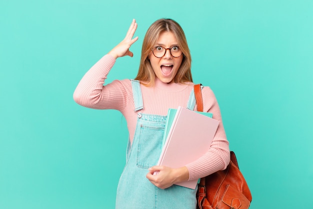 Young student woman screaming with hands up in the air