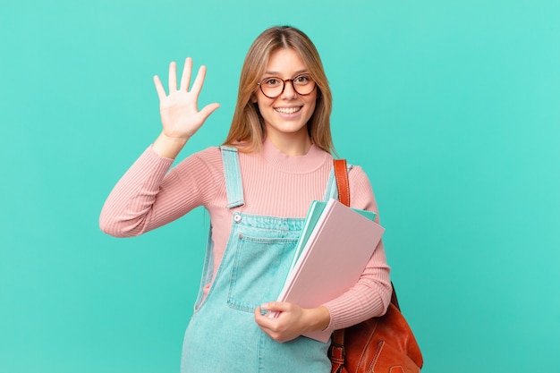 Young student woman smiling and looking friendly, showing number five