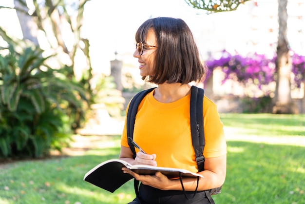 Young student woman win a park holding a notebook