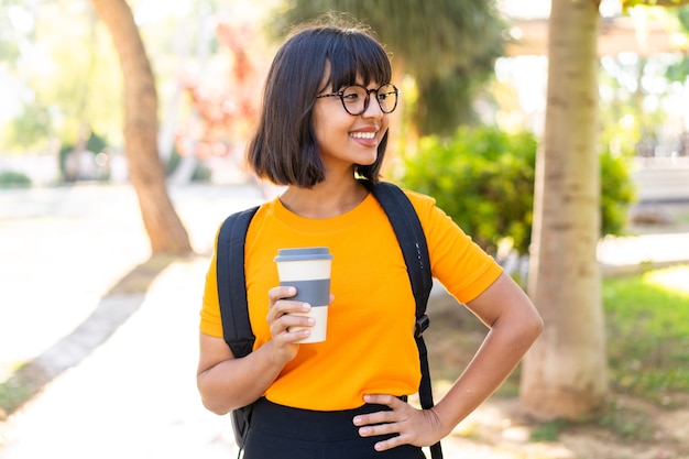 Young student woman win a park holding a take away coffee