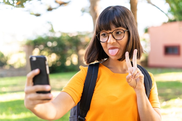 Young student woman win a park using mobile phone