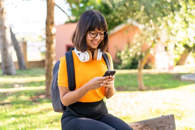 Young student woman win a park using mobile phone