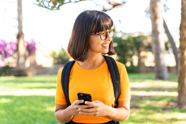 Young student woman win a park using mobile phone