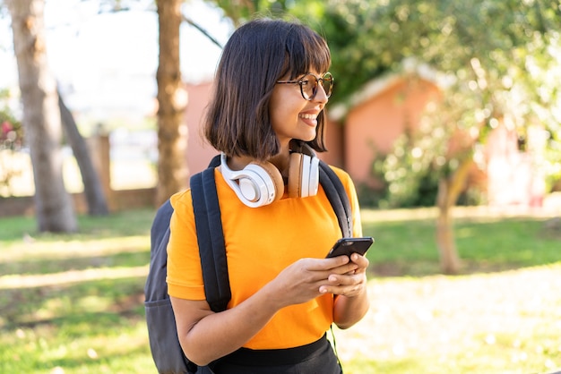 Young student woman win a park using mobile phone