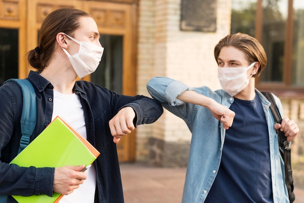 Young students touching elbows at university