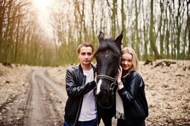 Young stylish couple in love near horse at autumn forest