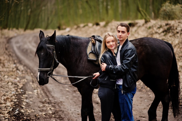 Young stylish couple in love near horse at autumn forest