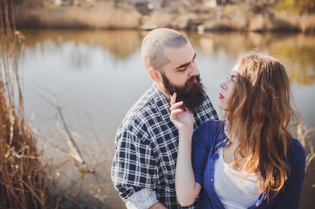 Young and stylish couple standing near water in park