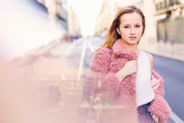 Young stylish girl traveler standing outdoors on the road in the city near boutiques