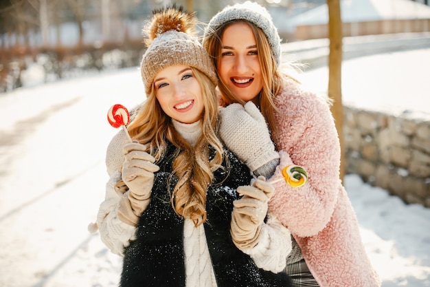 young and stylish girls in the winter clothes are walking in the solar park with sweets