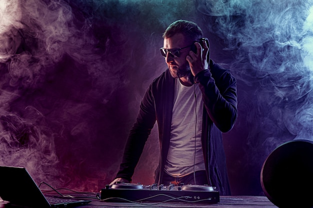 Young stylish man in glasses posing behind mixing console