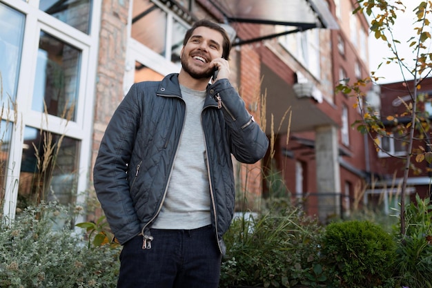 Young stylish man speaks on a mobile phone on the background of an office building