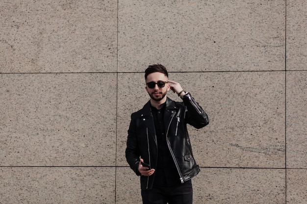 A young, stylish man with a mobile phone. The guy holds his hand to his head