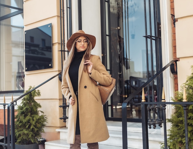 Young stylish woman dressed in a coat and felt hat. Autumn clothes. Street fashion