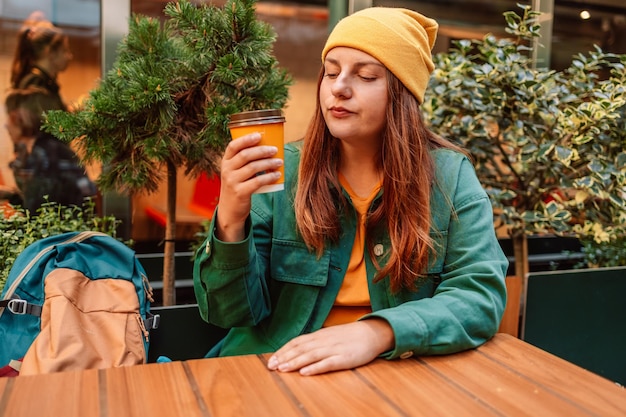 Young stylish woman drinking coffee to go in a city street