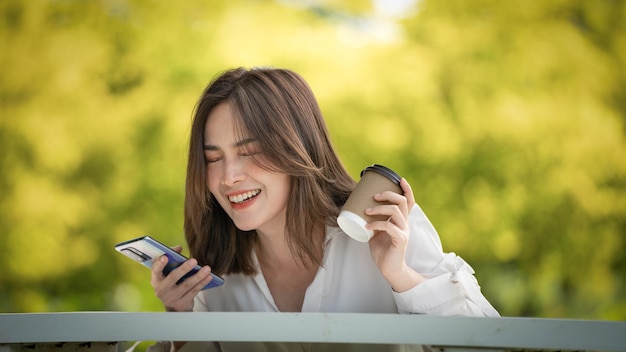 Young stylish woman drinking coffee and using paper cup and to go in a park young people female hand