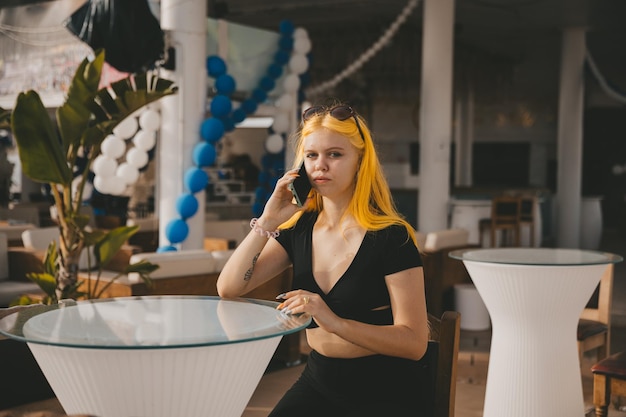 A young stylish woman talks on a mobile phone in a cafe