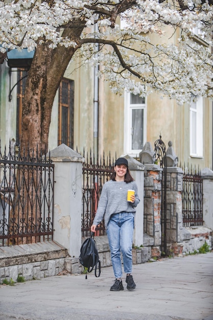 Young stylish woman walking by street with coffee cup