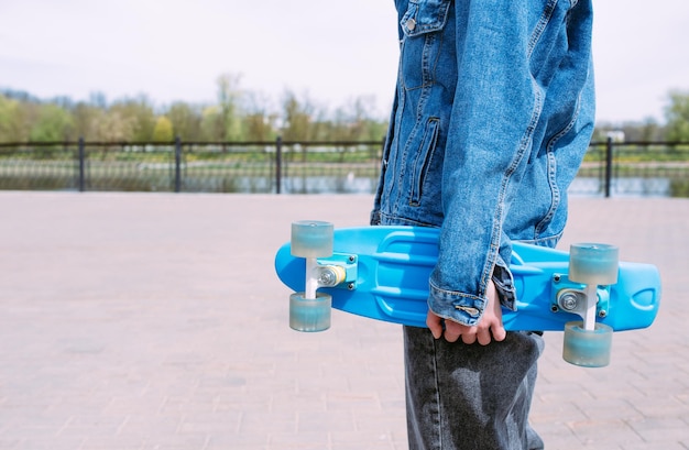 Young stylish woman wears sunglasses walks on the street with a skateboard