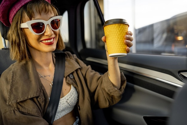 Young stylish woman with a coffee cup in car